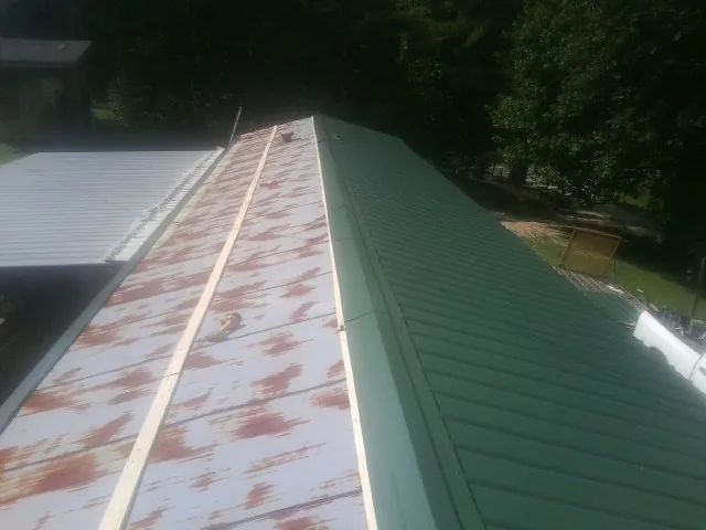 Old rusted panels beside newly installed green metal roofing — Wind Damage Roof Repair by Roofing Brothers in East Quogue