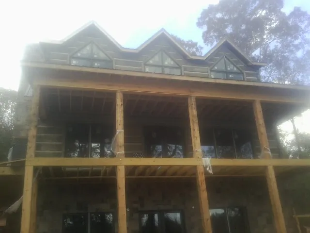 Dormers and porch framing on a large log home under construction — Roof Coating work by our crew in East Quogue