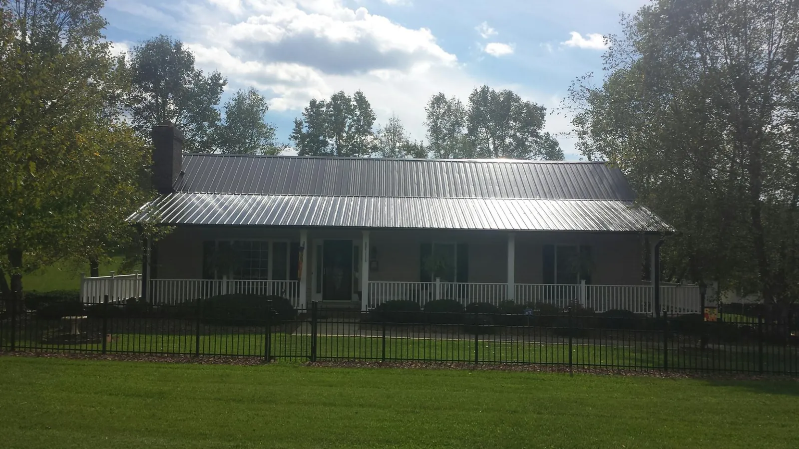 Gray metal roof on a brick ranch with a full width front porch — Gutter Guard Installation work by our crew in East Quogue