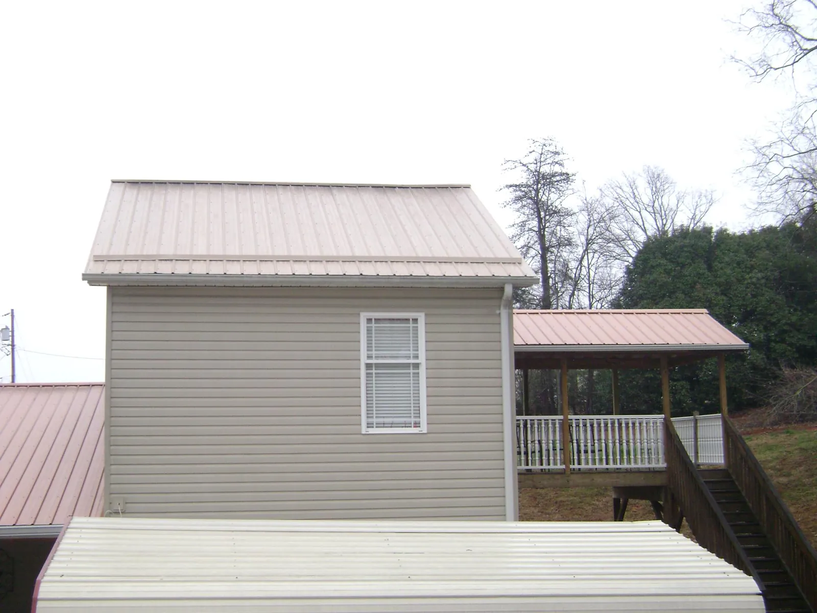 Tan metal roofs on a two story addition and attached porch, from a Roof Replacement job in East Quogue