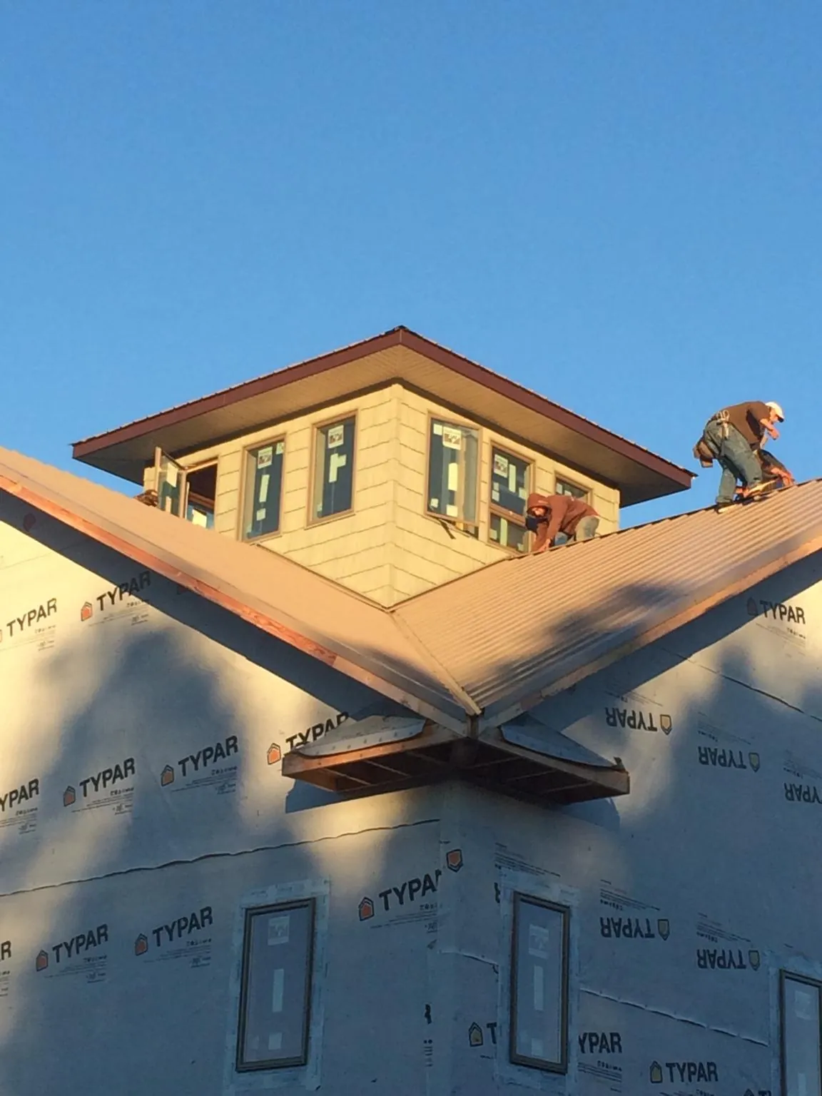 Roofers working around a rooftop cupola on a new metal roof at sunset — Roof Waterproofing in East Quogue by Roofing Brothers